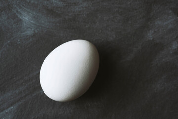White chicken egg on black background