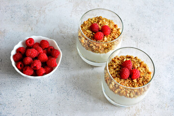 healthy cheesecake in drinking glass with granola, yoghurt and fresh raspberry isolated, topview
