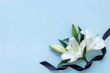 White liles flowers and black ribbon as symbol of the funeral. Mourning concept