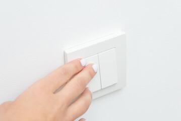 Close up of hand turning on or off light in room. Hand on wall light switcher