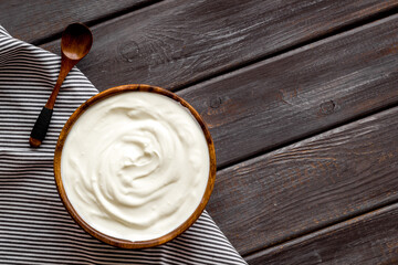 Fototapeta na wymiar White dip sauce - sour cream or yogurt in wooden bowl