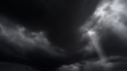 Obraz premium dark dramatic sky with black stormy clouds before rain or snow as abstract background, extreme weather, the sun shines through the clouds, high contrast photo