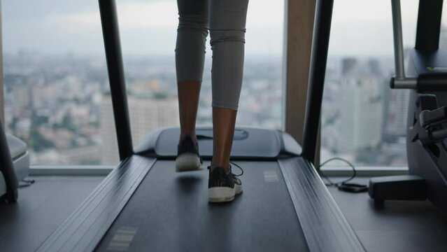 Close up of black woman legs using a treadmill with bangkok skyline on the background