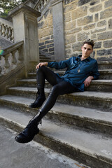 portrait of handsome brunette male model wearing fantasy medieval prince costume, romantic silk shirt. Wandering around historical castle location background with stone staircase.