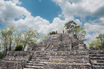 Fototapeta na wymiar Woman climbing stairs of the maya pyramid ruins of Calakmul at summer