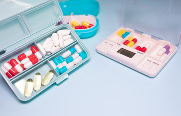Plastic box with different pills on light blue background, top view. Space for text. 