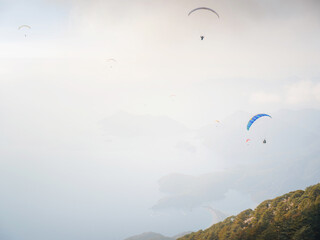 Paragliding in sky. Paraglider tandem flying over sea and mountains in cloudy day. view of paraglider and Blue Lagoon in Oludeniz, Turkey. Extreme sport. Landscape