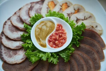 Sliced meat, garnished with vegetables and sauces