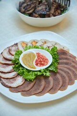 Sliced meat, garnished with vegetables and sauces
