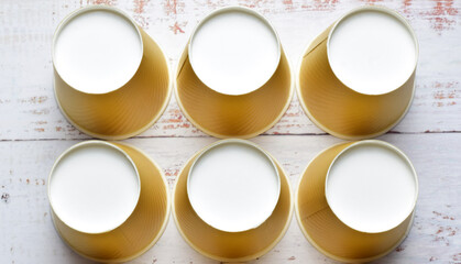 Recycled paper and cardboard cups, on a light colored rustic table. Zenith view.