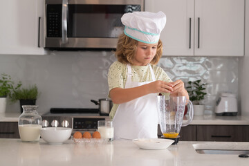 Kid chef cook is learning how to make a cake in the home kitchen. Child making tasty delicious. Eggs, milk and flour ingredients for baking cookies or pancakes.