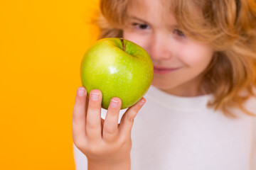 Fototapeta na wymiar Kid with apple in studio. Studio portrait of cute child hold apple isolated on yellow background.