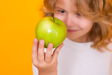 Kid with apple in studio. Studio portrait of cute child hold apple isolated on yellow background.