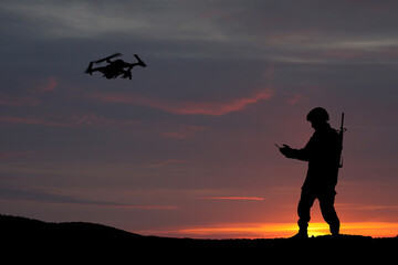 Silhouettes of soldiers are using drone and laptop computer for scouting during military operation against the backdrop of a sunset. Greeting card for Veterans Day, Memorial Day, Independence Day.