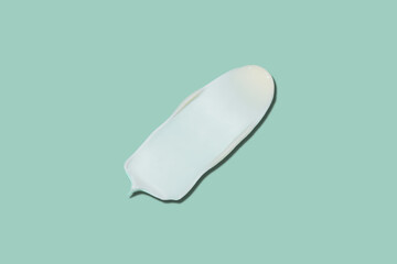 White cosmetic cream texture, skincare lotion swatch on pastel green background. Face creme, body moisturiser, hair conditioner smear smudge stroke. Creamy beauty product closeup