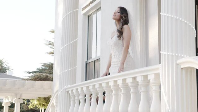Bride posing by balcony as she is photographed. Looking over shoulder. Outdoor mansion wedding. Shot in 4K 60 FPS. To purchase entire event raw at wholesale price email willneatheryyahoo.com.