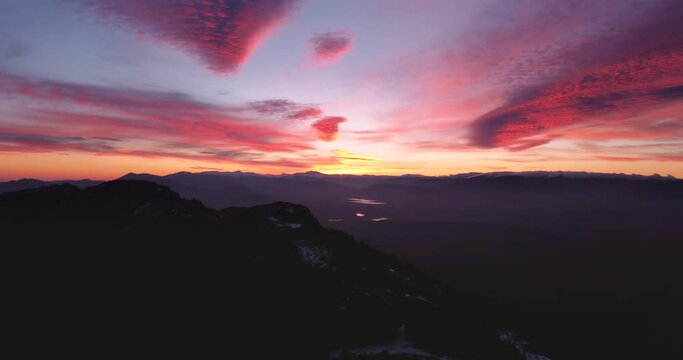 Silhouette Aerial view flying sideways  parallax efect during incredible colorful sunset in winter with snow on mountain peaks in Madrid, Spain.
