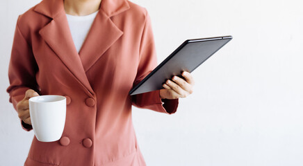 Portrait of a businesswoman holding a cup of coffee and a tablet, white background