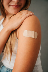 Close up female sitting and looking at band aid on her arm