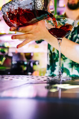 man bartender hand making red cocktail on bar