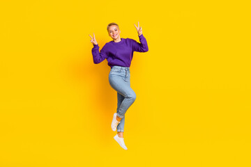 Fototapeta na wymiar Full length portrait of overjoyed friendly person jumping demonstrate v-sign isolated on yellow color background