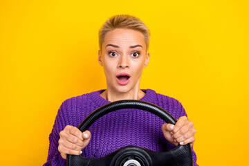 Portrait of positive impressed astonished woman with short hair violet sweater hold steering wheel isolated on yellow color background