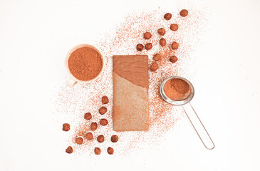 Chocolate bar with hazelnuts around it sprinkled with cocoa