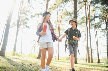 Fototapeta premium Little boy and girl go hiking on a forest road
