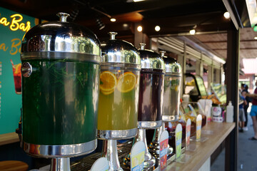 People near the outdoor bar with glass bottles with different fruit drinks