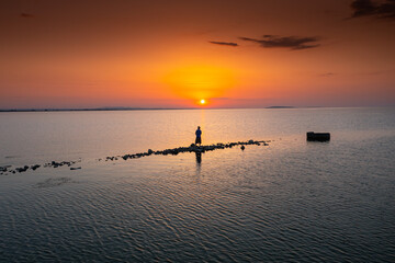 Fototapeta premium Aerial view of a fisherman on a lake during sunrise, fishing in a lake