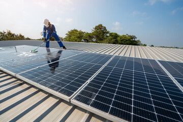 Technician using a mop and water to clean the solar panels that are dirty with dust and birds'...