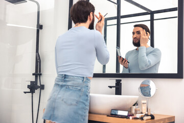 Male looking at himself during the eye makeup application