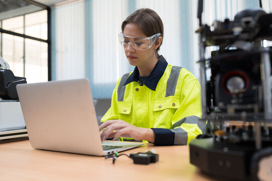 Female engineer using laptop computer for training Programmable logic controller. Woman programmer create programmable computer for control AI robot in the robotics laboratory room