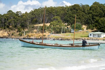 Naklejka na ściany i meble man watching wooden boat on the water, at the wooden boat festival in hobart tasmania australia
