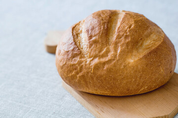 Fresh delicious bread close-up. Freshly baked sourdough bread with a golden crust on a wooden board. The context of a bakery with delicious bread. Confectionery products.