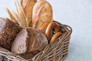 Assortment of fresh bread in a wicker basket close-up. Freshly baked bread on the table. The context of a bakery with delicious bread. Confectionery products.