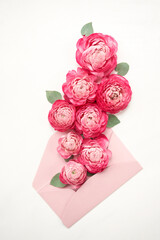 Love letter. white card with pink paper envelope mock up. Petals of flowers, roses and ranunculus. Valentine's day romantic background . Space for text.