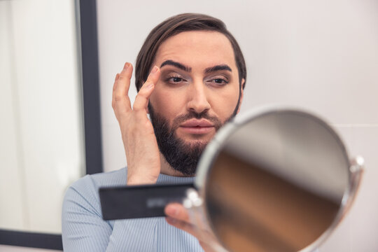 Male looking at himself in the mirror during makeup application
