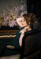 beautiful romantic brunette woman sitting on a piano with flowers in dark vintage room