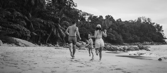 family running on the beach. Black and white toned image