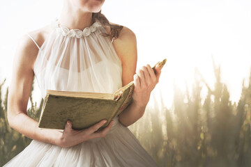 woman reading a book in the meadow in the middle of nature, knowledge concept