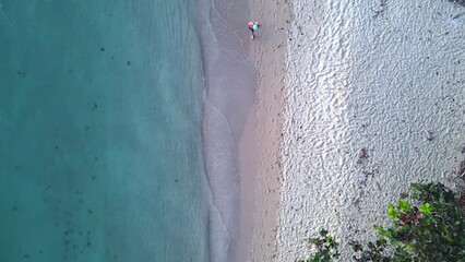 Man walking along coastline waves beach. Nice aerial view flight vertical drone - Powered by Adobe