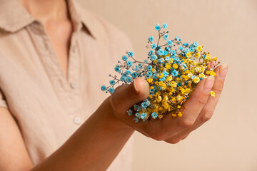 Yellow-blue gypsophila flowers in a woman's hand. Ukrainian symbols