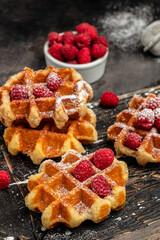 Belgian waffles with raspberries with sugar powder in a freeze motion of a cloud of powder midair, served with jug of milk. Delicious breakfast or snack