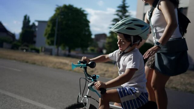 Small boy losing equilibrium from bicycle. mother catching falling child while learning to ride bike