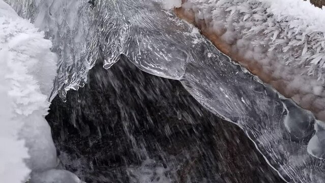 Deep frozen creek with ice formation and a old wooden chute for powering an old corn mill