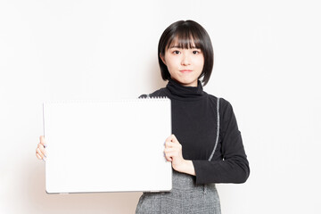 大きいスケッチブックを見せている若い女性