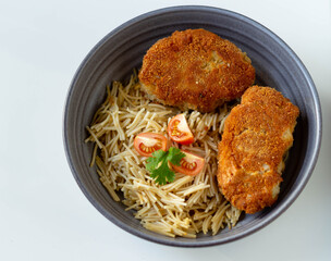 Chicken cutlets with pasta and cherry tomatoes and parsley in a gray plate on a white background. Top view.