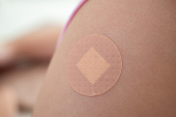 Vaccinated little asian girl with adhesive plaster after vaccine injection