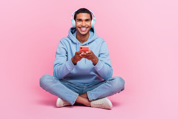 Photo of funky cool glad man wear stylish clothes sitting floor use modern device listen audio song...